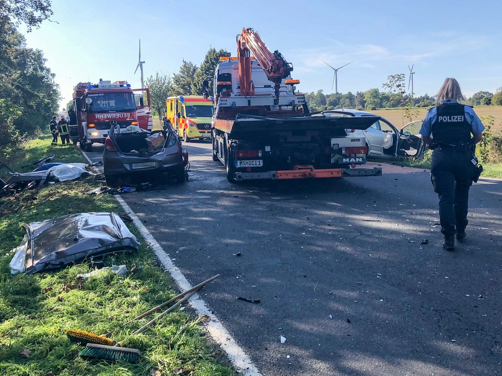 Eine Polizistin geht über die Unfallstelle auf der Landstraße L 151.