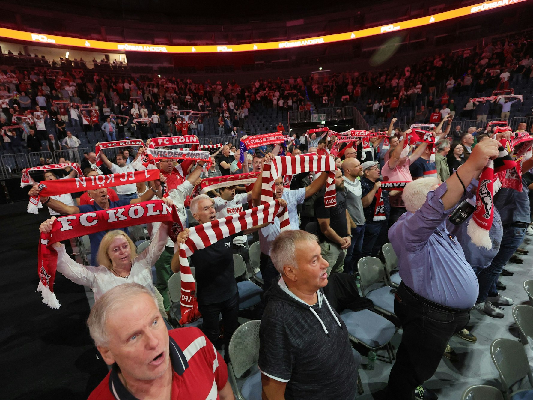 Fans singen bei der Mitgliederversammlung die Hymne und halten ihre Schals in die Höhe.