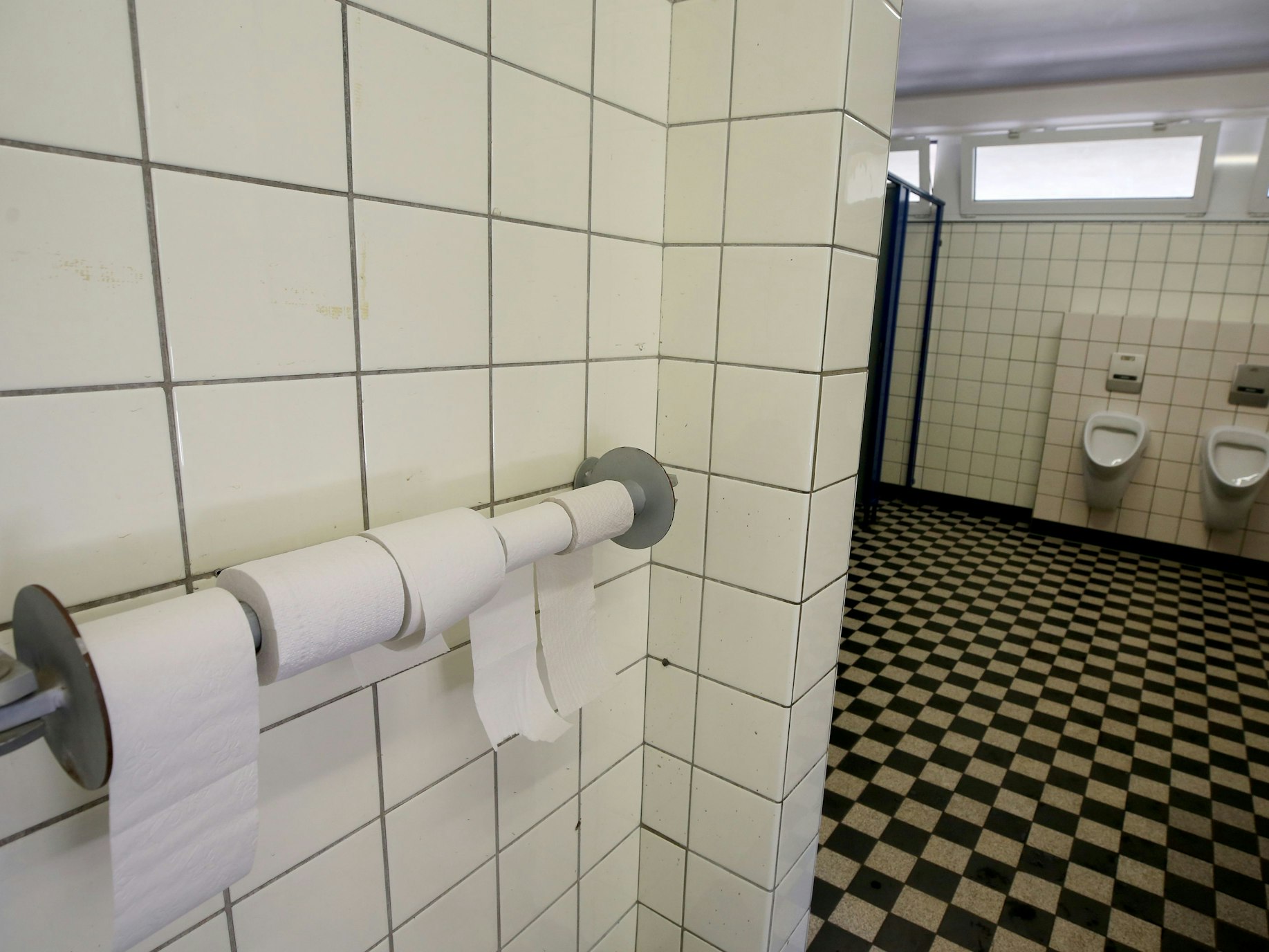 Mit einem Hängeschloss gesicherte Toilettenpapierrollen hängen in einer noch nicht renovierten Toilette einer Grundschule.