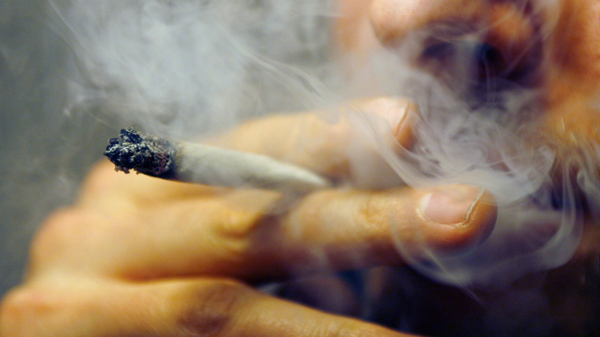 Ein Mann raucht einen Joint mit Marihuana.