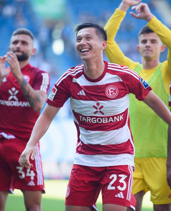 Nicolas Gavory, Shinta Appelkamp, Karol Niemczycki und Emmanuel Iyoha jubeln nach dem 3:1 von Fortuna Düsseldorf beim FC Hansa Rostock vor der Fan-Kurve.