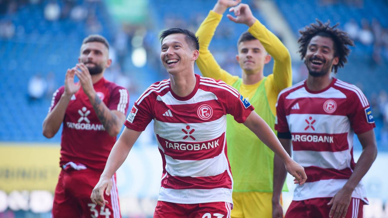 Nicolas Gavory, Shinta Appelkamp, Karol Niemczycki und Emmanuel Iyoha jubeln nach dem 3:1 von Fortuna Düsseldorf beim FC Hansa Rostock vor der Fan-Kurve.