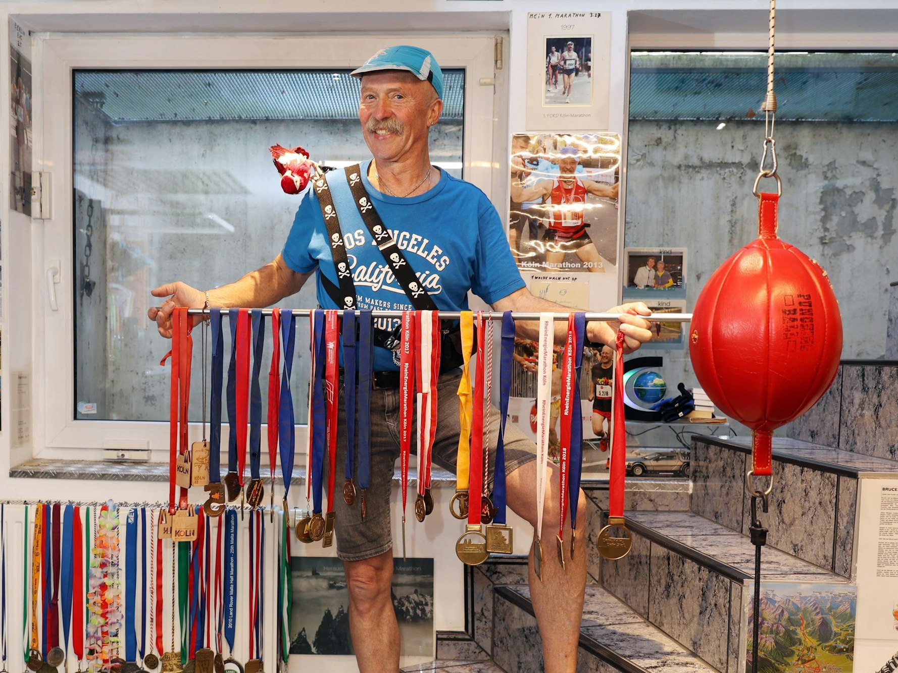 Gerd Mausbach hält eine Stange, auf der mehrere Medaillen hängen.