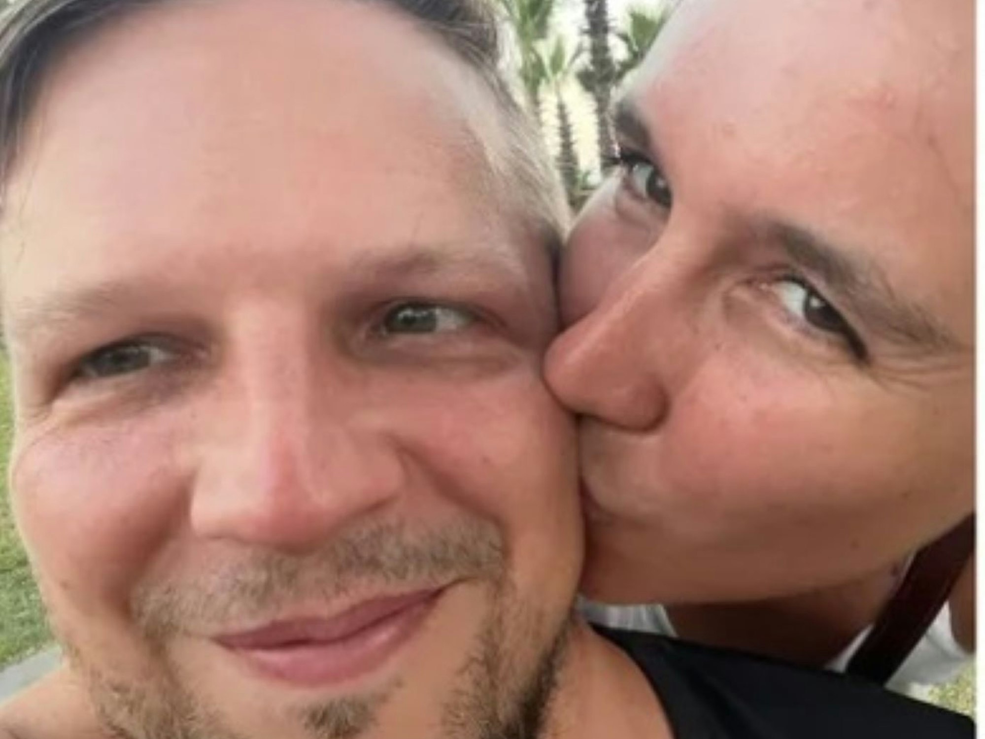 Sabrina küsst ihren Ehemann von hinten auf die Wange.