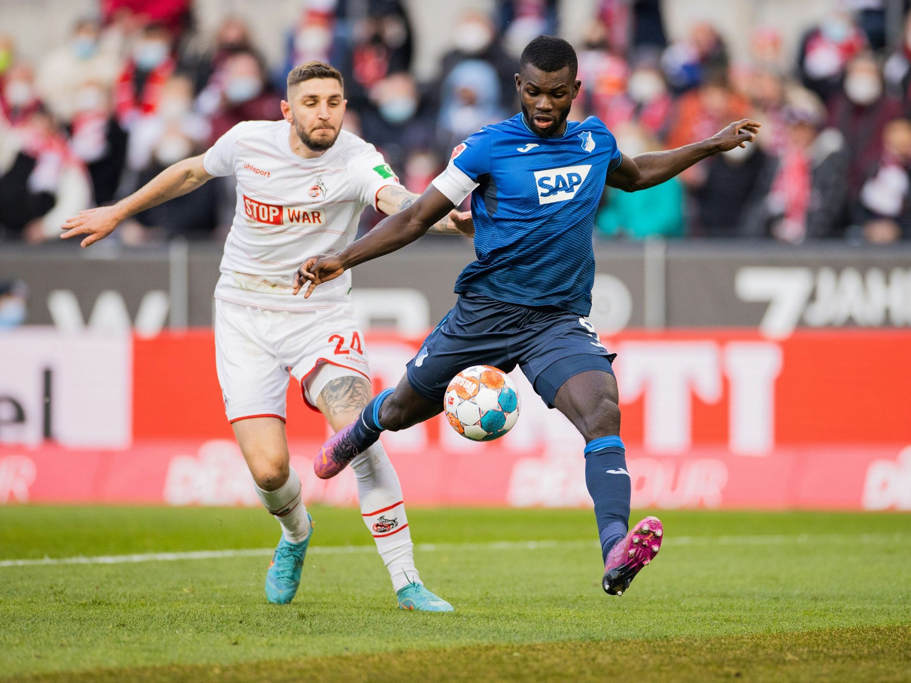 Kölns Jeff Chabot (l) und Hoffenheims Ihlas Bebou versuchen an den Ball zu kommen.