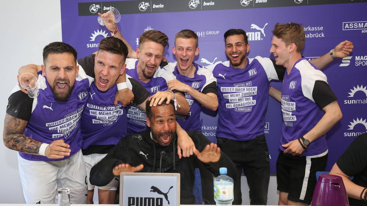Die Spieler von Osnabrück feiern den Aufstieg in die 2. Bundesliga und überraschen ihren Trainer Daniel Thioune (M) bei der Pressekonferenz mit einer Bierdusche.