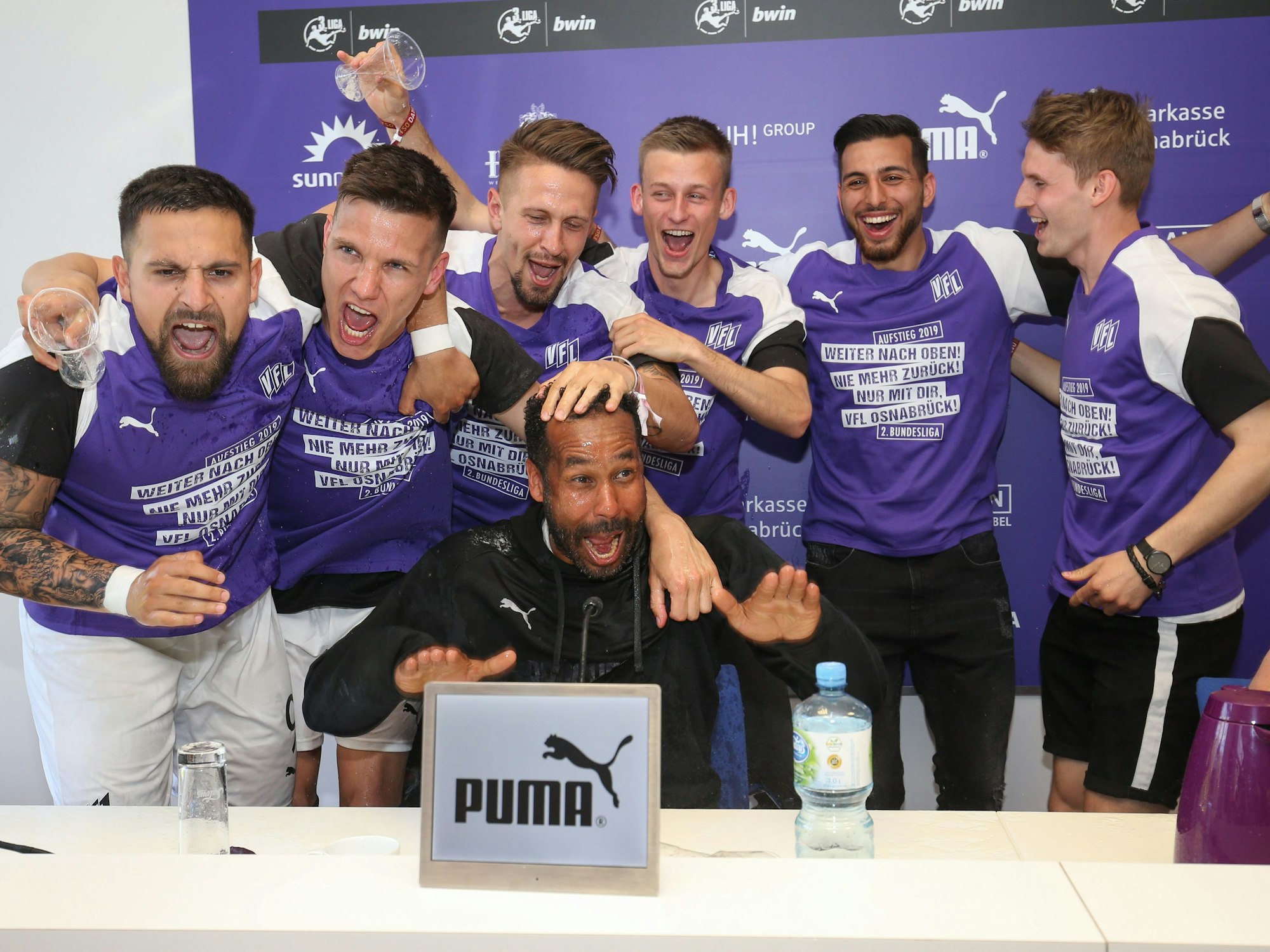 Die Spieler von Osnabrück feiern den Aufstieg in die 2. Bundesliga und überraschen ihren Trainer Daniel Thioune (M) bei der Pressekonferenz mit einer Bierdusche.