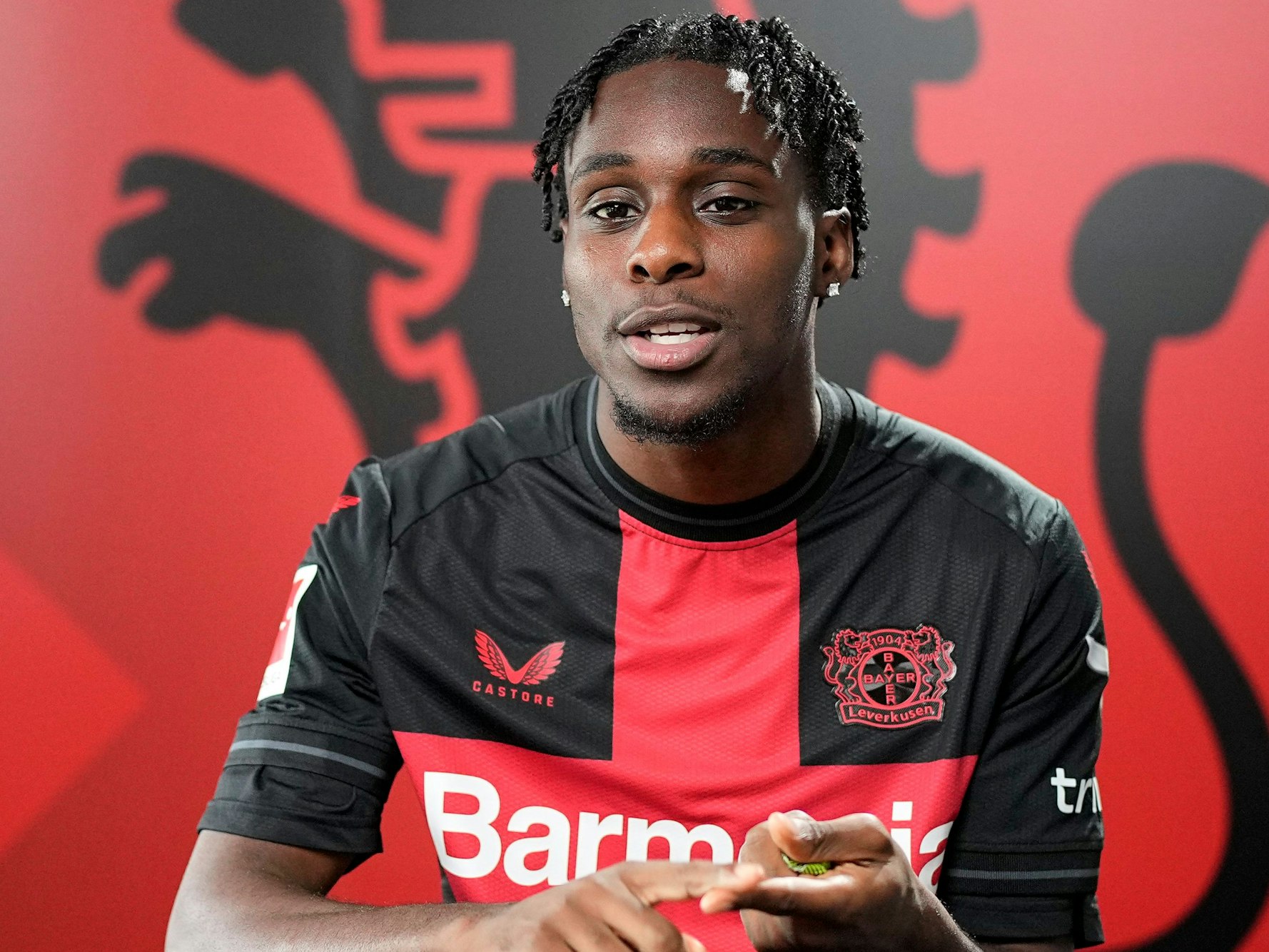 Jeremie Frimpong von Bayer Leverkusen zählt etwas auf.