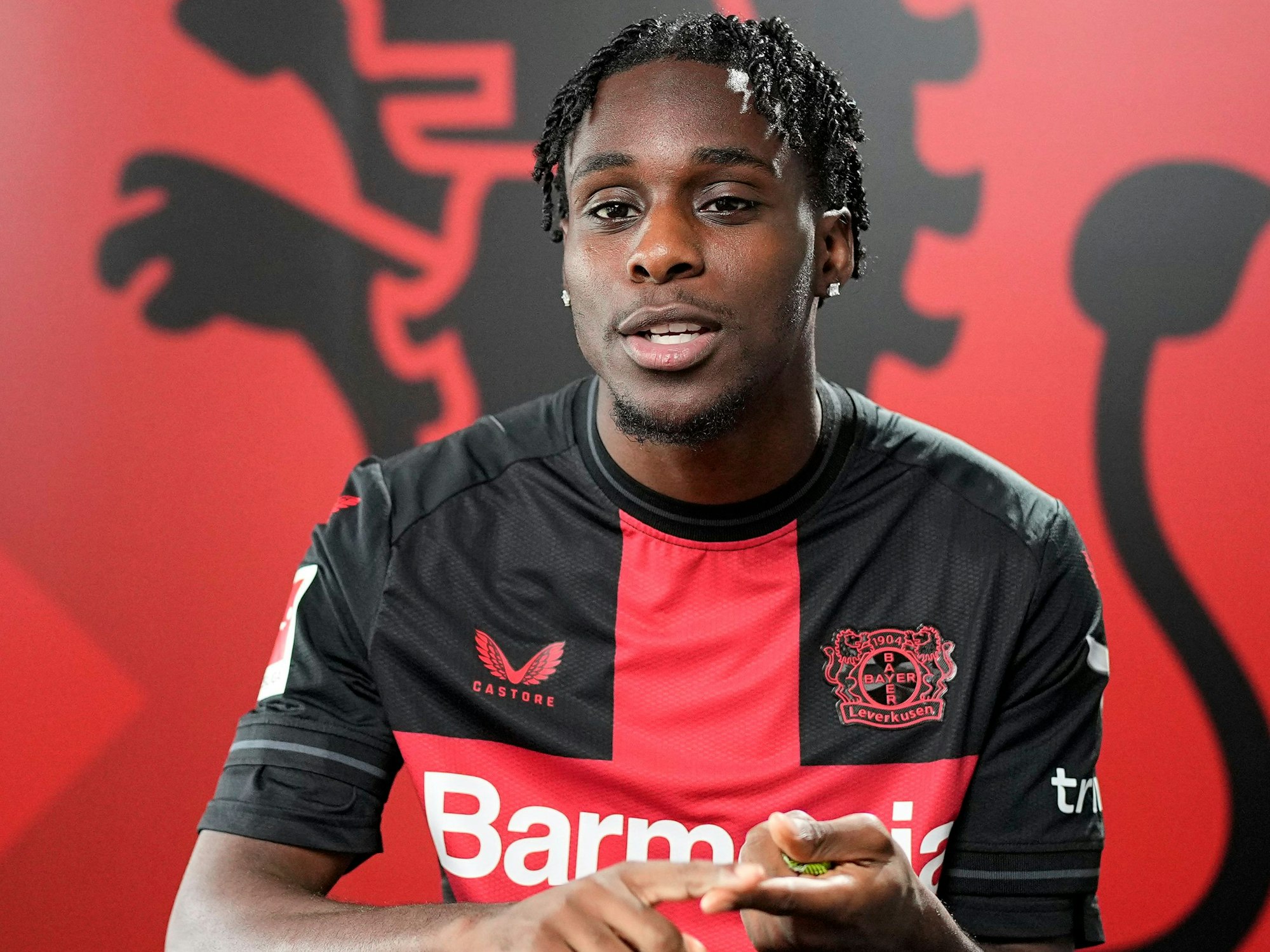 Jeremie Frimpong von Bayer Leverkusen zählt etwas auf.