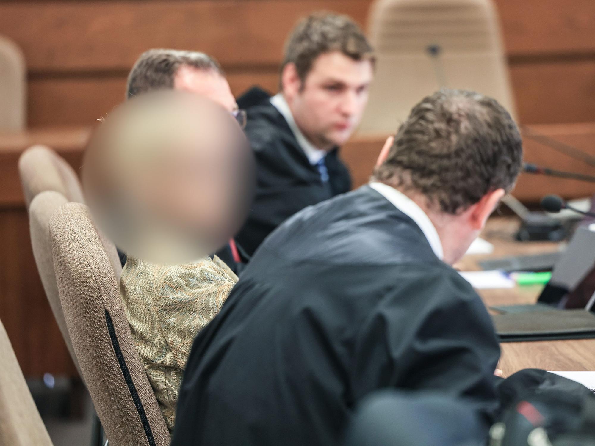 Die Apothekerin und ihre Verteidiger sitzen im Gerichtssaal und sprechen miteinander.