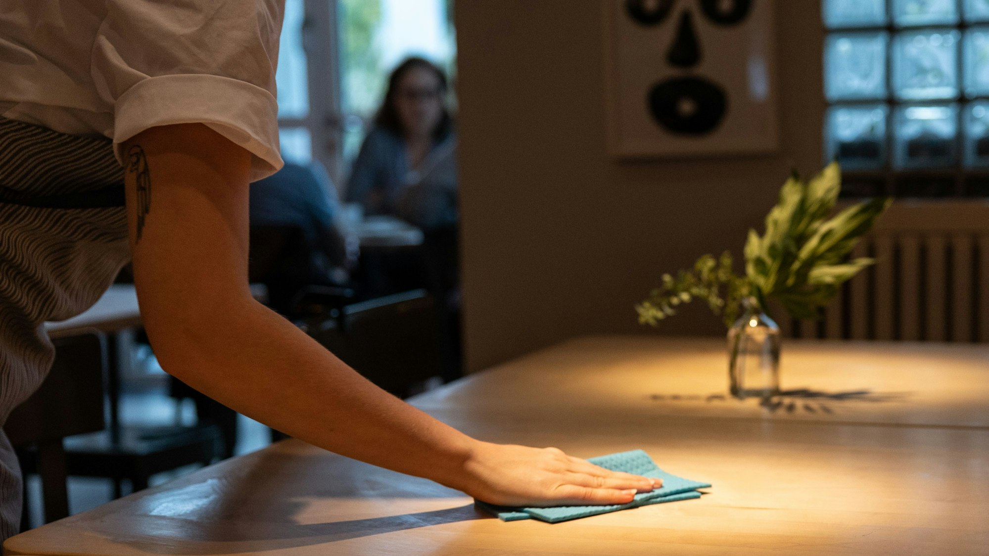 Eine Bedienung wischt einen Tisch im Restaurant sauber.