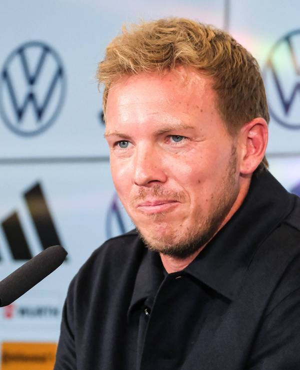 Julian Nagelsmann sitzt auf einer Pressekonferenz vor einem Mikrofon.