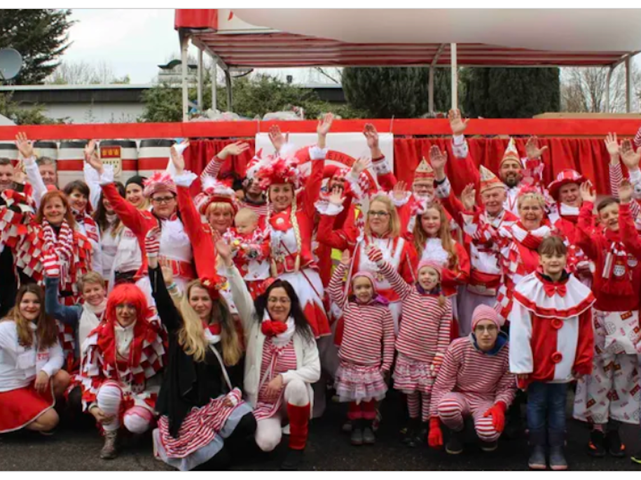 Mitglieder vom FMK lächeln beim Karnevalsumzug in Merheim in die Kamera.