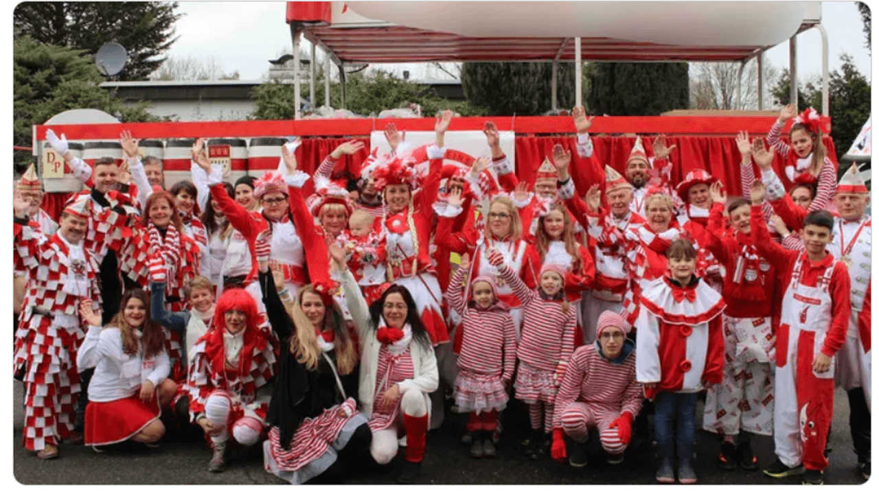 Mitglieder vom FMK lächeln beim Karnevalsumzug in Merheim in die Kamera.