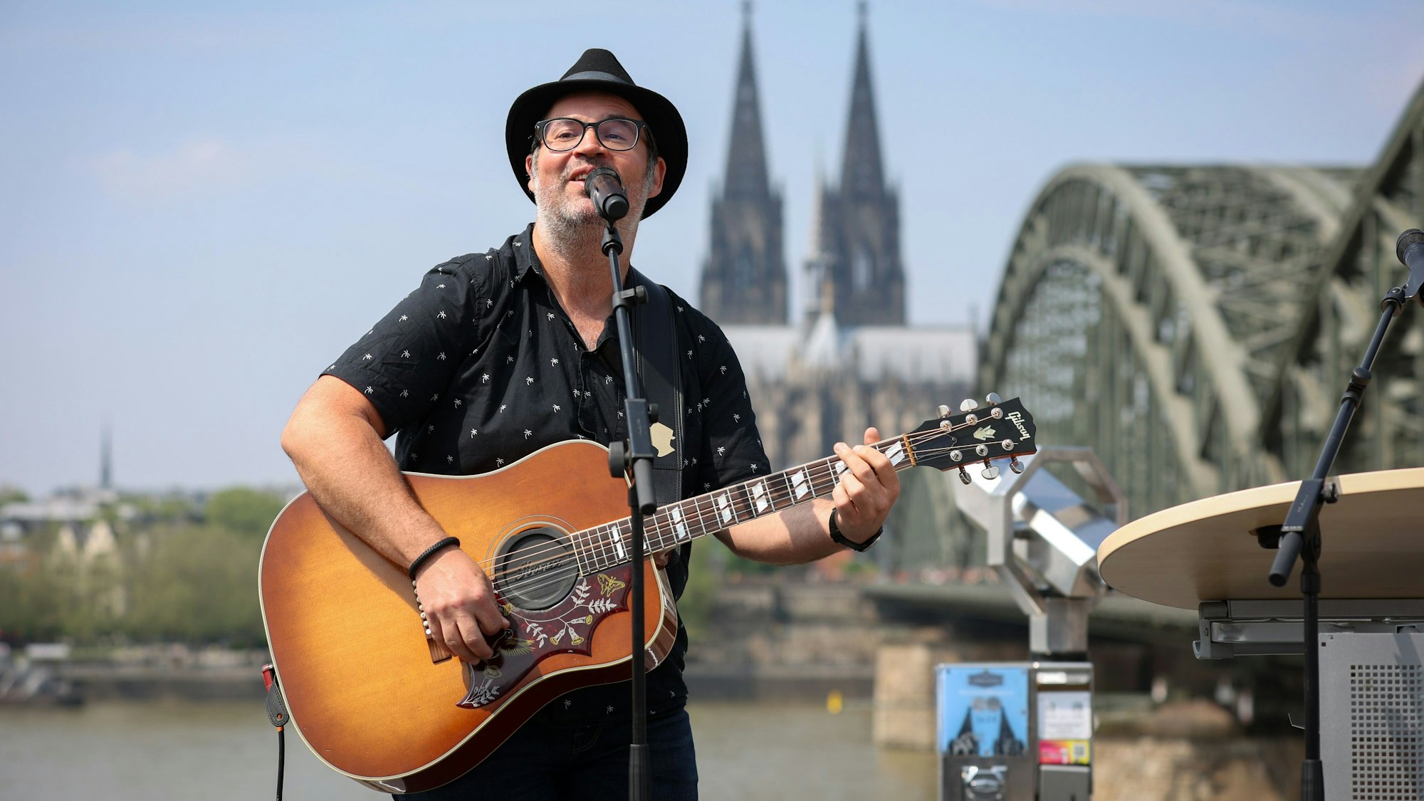 Björn Heuser singt mit seiner Karriere am Rhein vor dem Panorama von Dom und Hohenzollernbrücke.