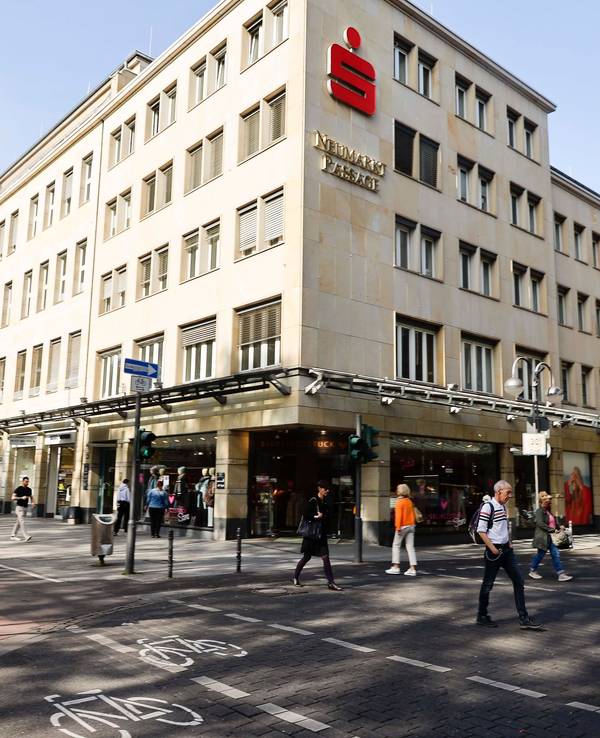Blick auf das Sparkassen-Gebäude am Kölner Neumarkt, dutzende Menschen gehen davor vorbei.