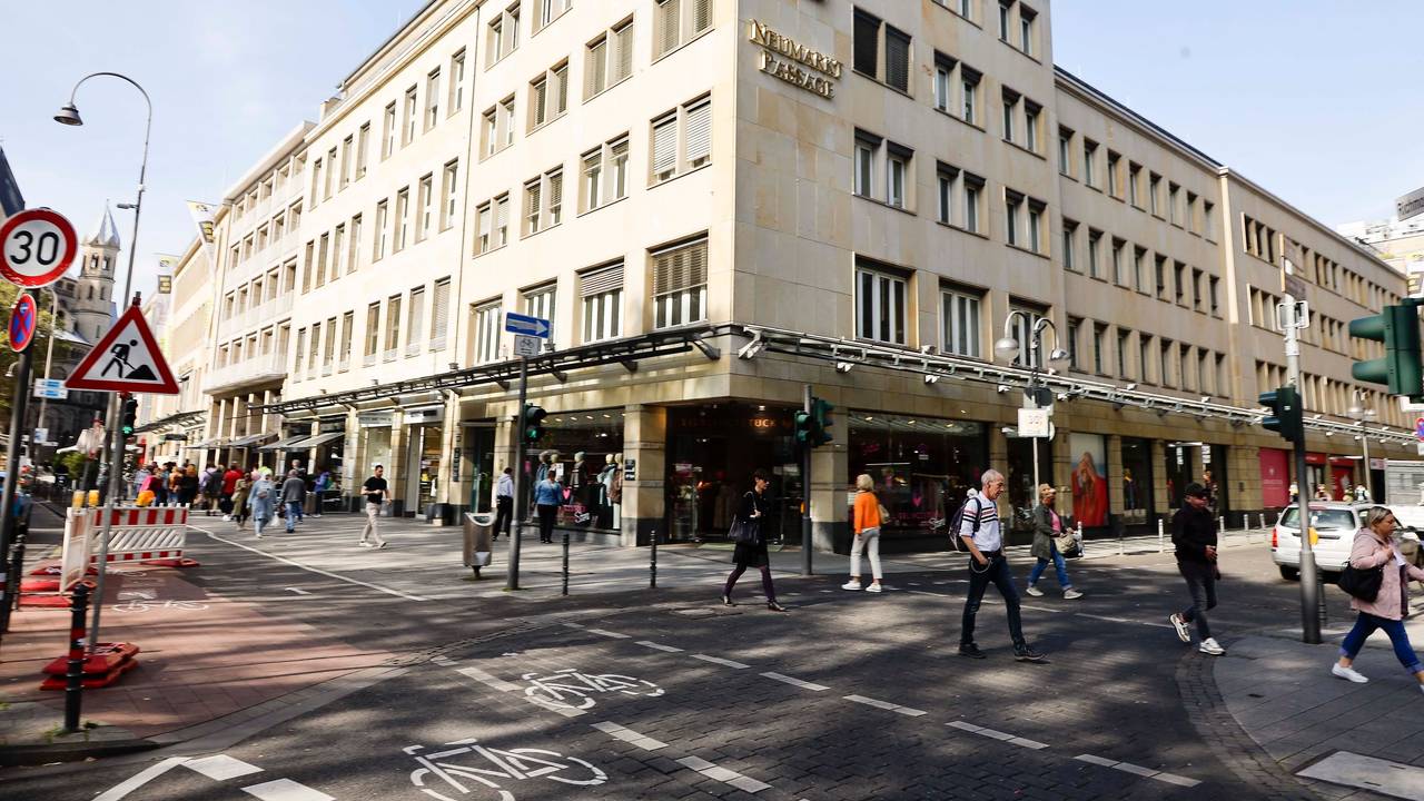 Blick auf das Sparkassen-Gebäude am Kölner Neumarkt, dutzende Menschen gehen davor vorbei.