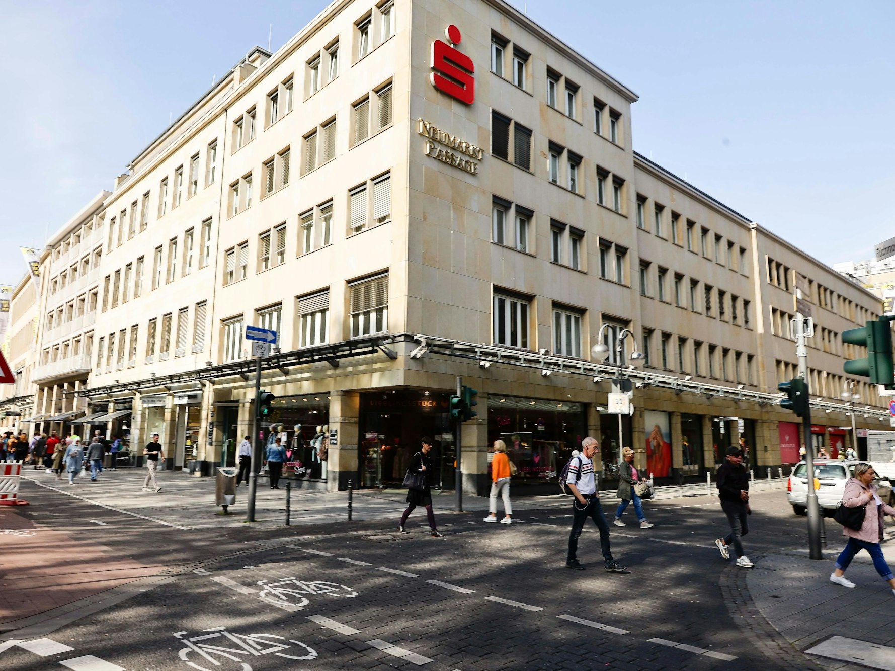 Blick auf das Sparkassen-Gebäude am Kölner Neumarkt, dutzende Menschen gehen davor vorbei.