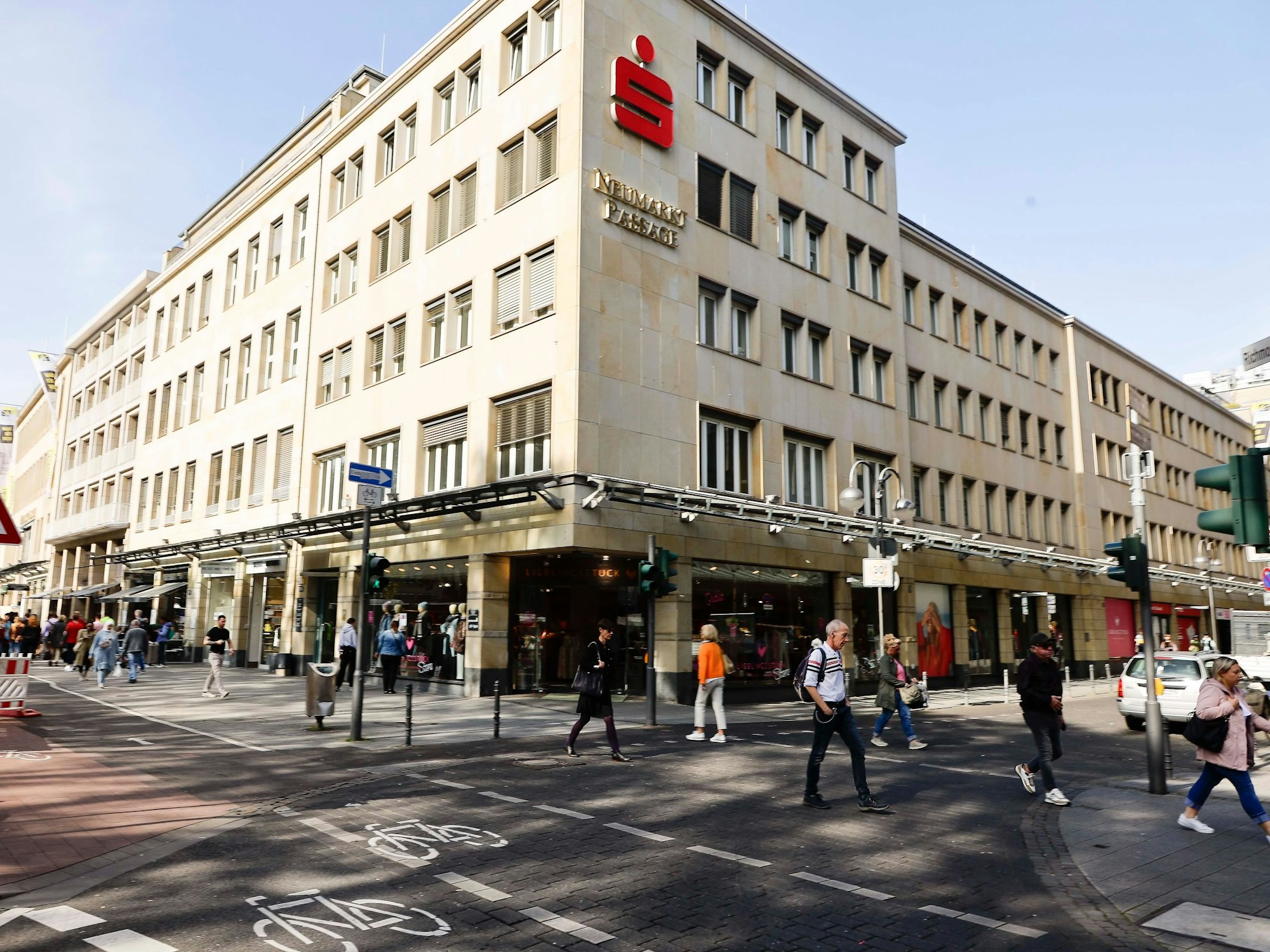 Blick auf das Sparkassen-Gebäude am Kölner Neumarkt, dutzende Menschen gehen davor vorbei.