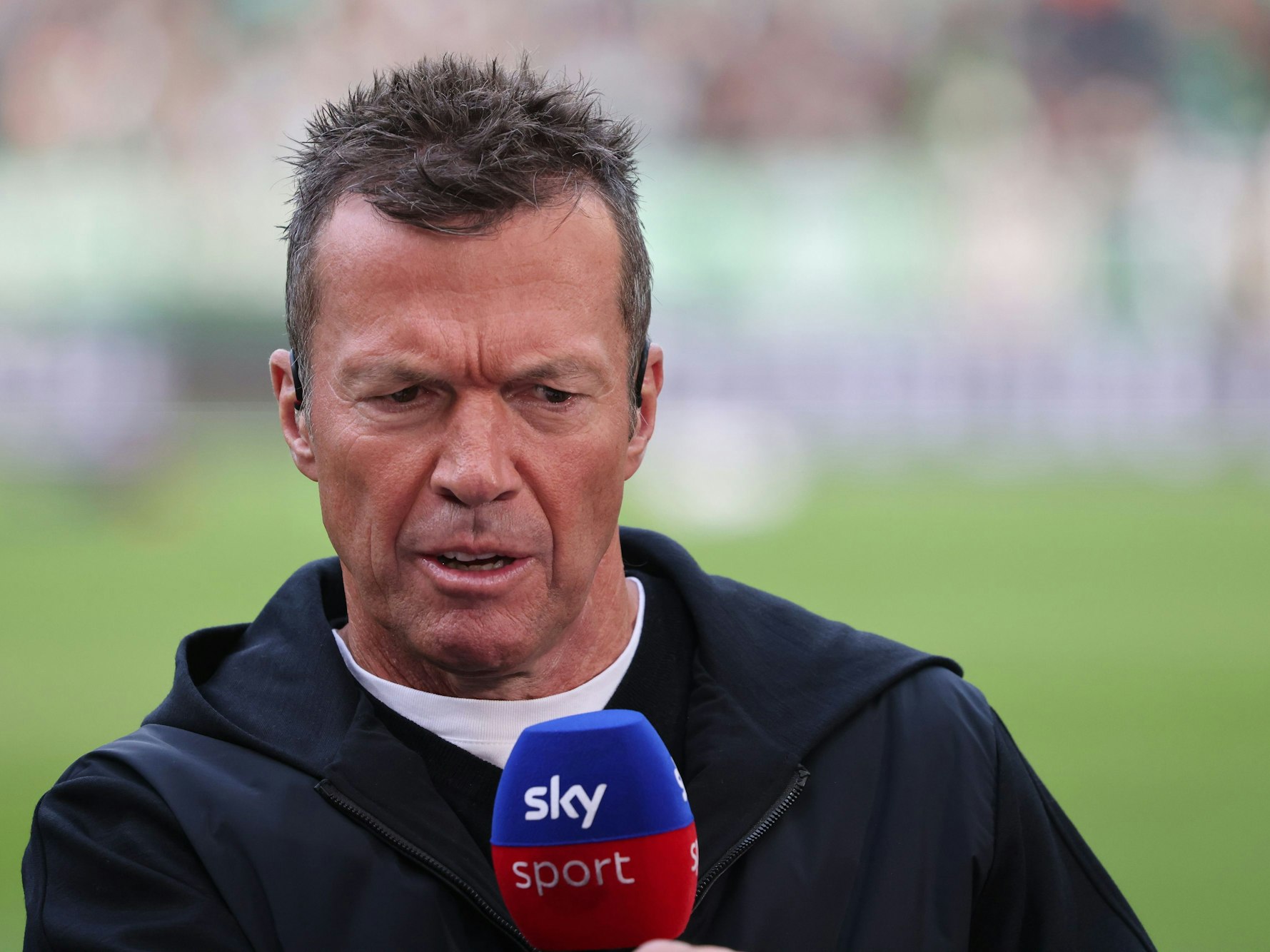 Lothar Matthäus spricht in ein blau-rotes Mikro mit Sky-Logo.