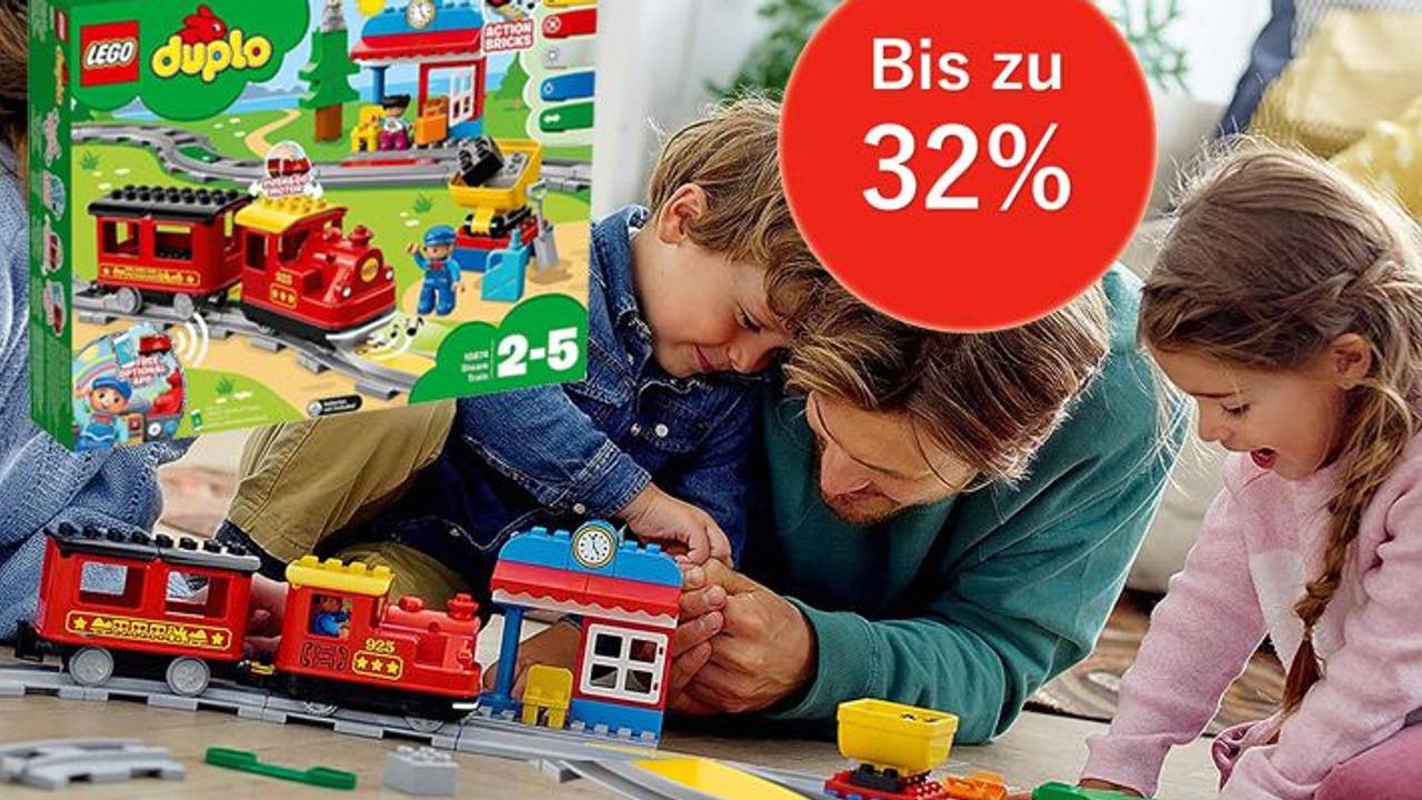 Auf dem Bild ist eine Familie zu sehen, die mit der Lego Duplo Eisenbahn spielt.