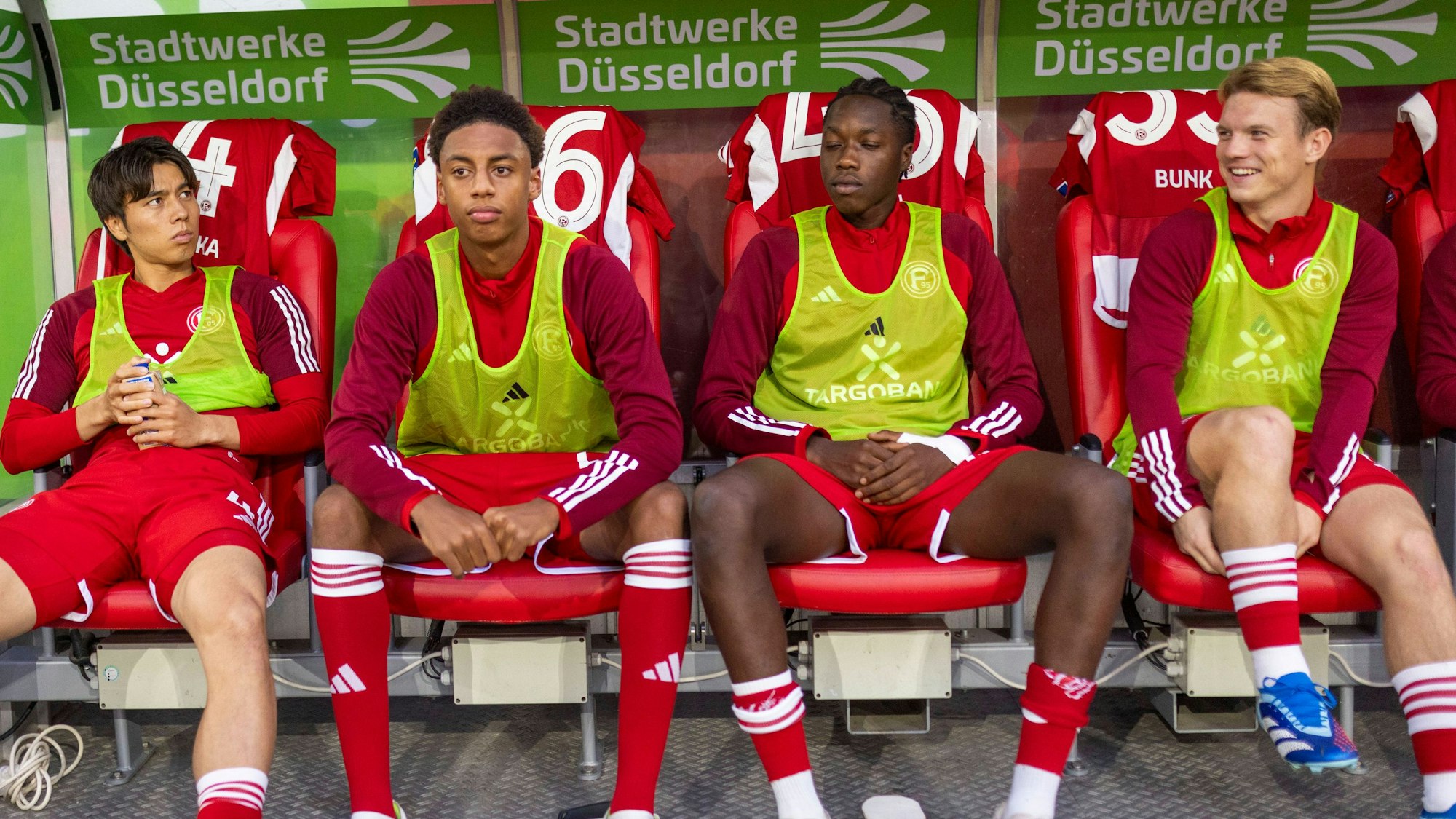 Fortuna Düsseldorfs Ao Tanaka, Sima Suso, King manu und Daniel Bunk sitzen beim Spiel gegen den VfL Osnabrück auf der Auswechselbank.