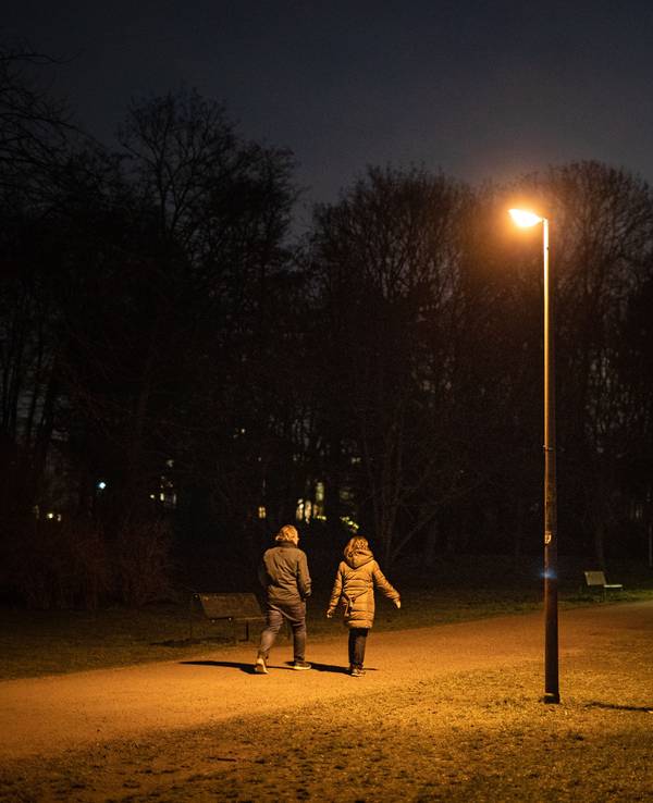 Zwei Personen gehen durch einen dunklen Park in Köln.