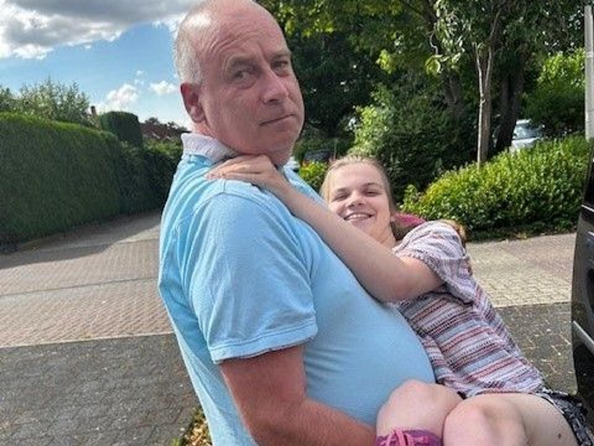 Ein Mann trägt seine 16-jährige Tochter ins Auto.