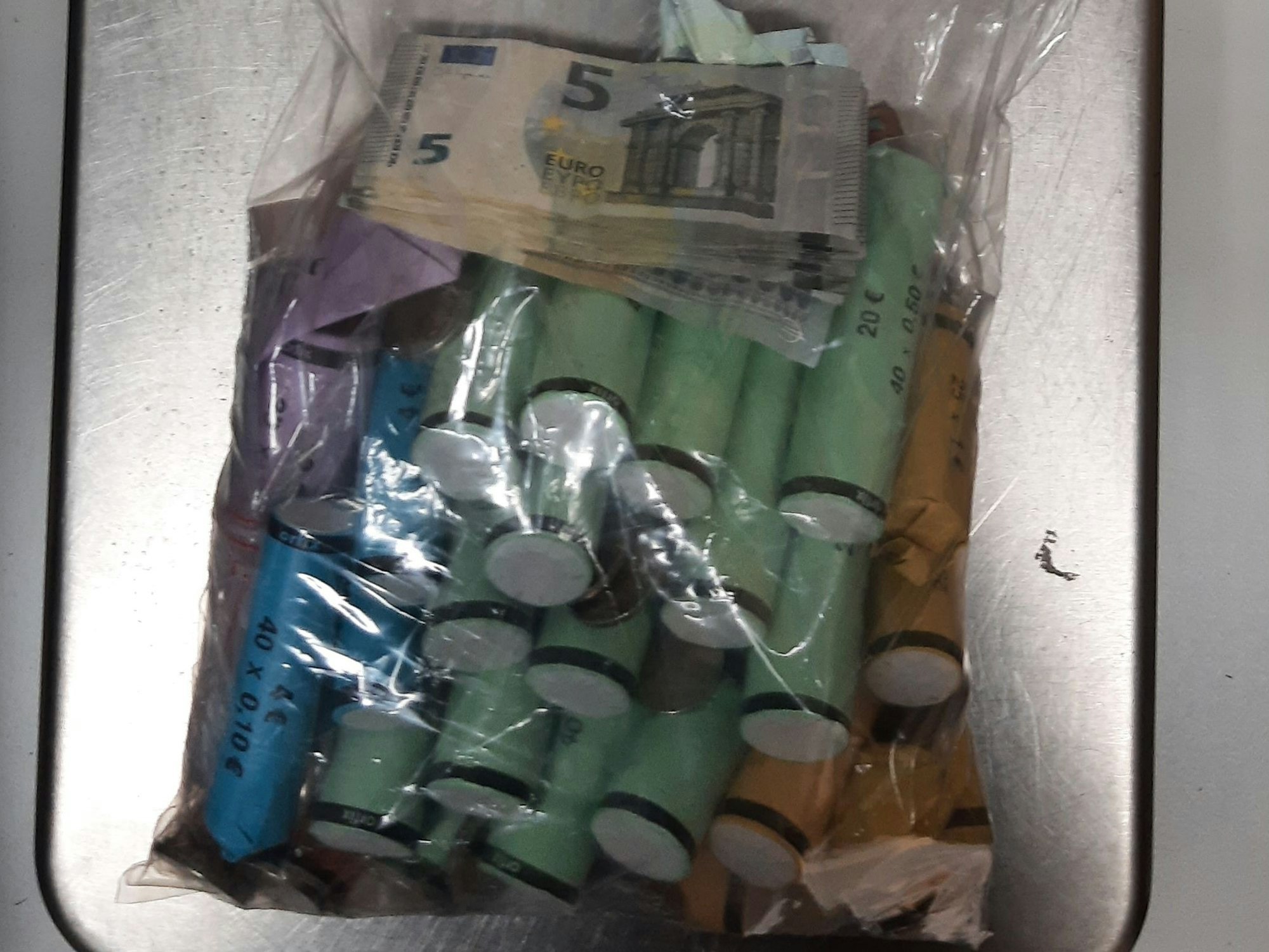 Eingerollte Münzen liegen in einer Plastiktüte auf einer Waage.