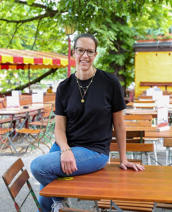 Hellers Chefin Anna Heller sitzt auf einem Tisch im Biergarten am Volksgarten.