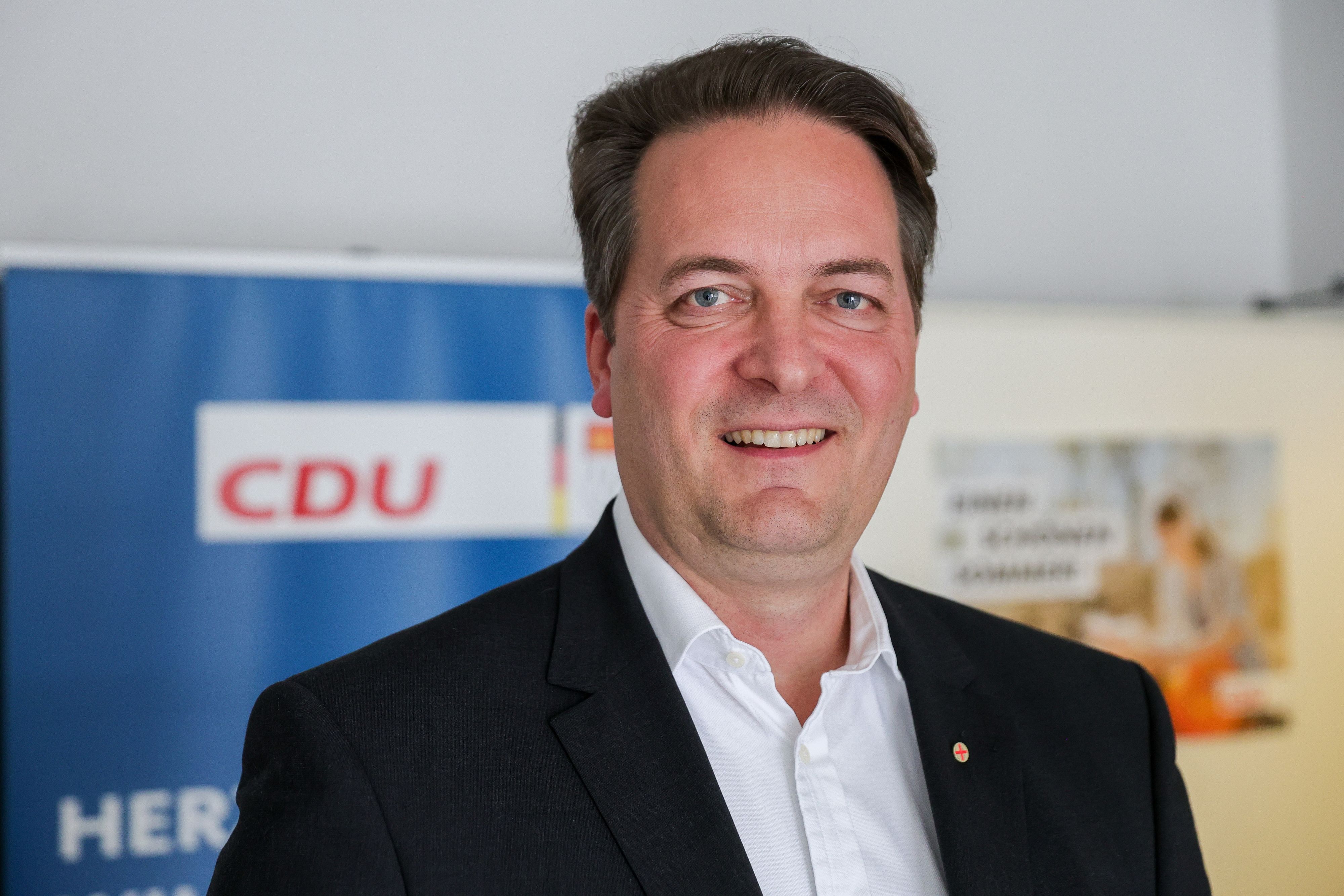 CDU-Chef Karl Alexander Mandl lächelt auf einer Pressekonferenz in die Kamera.