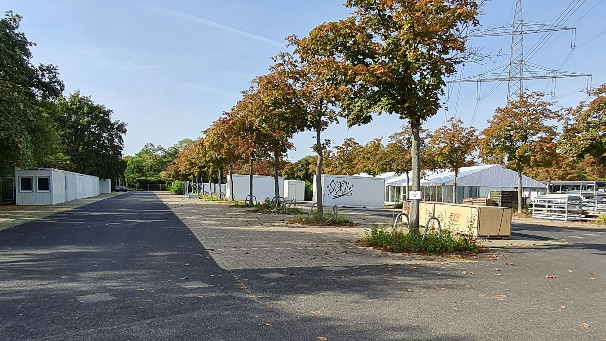 Auf einem Parkplatz stehen mehrere Container sowie ein großes Zelt.