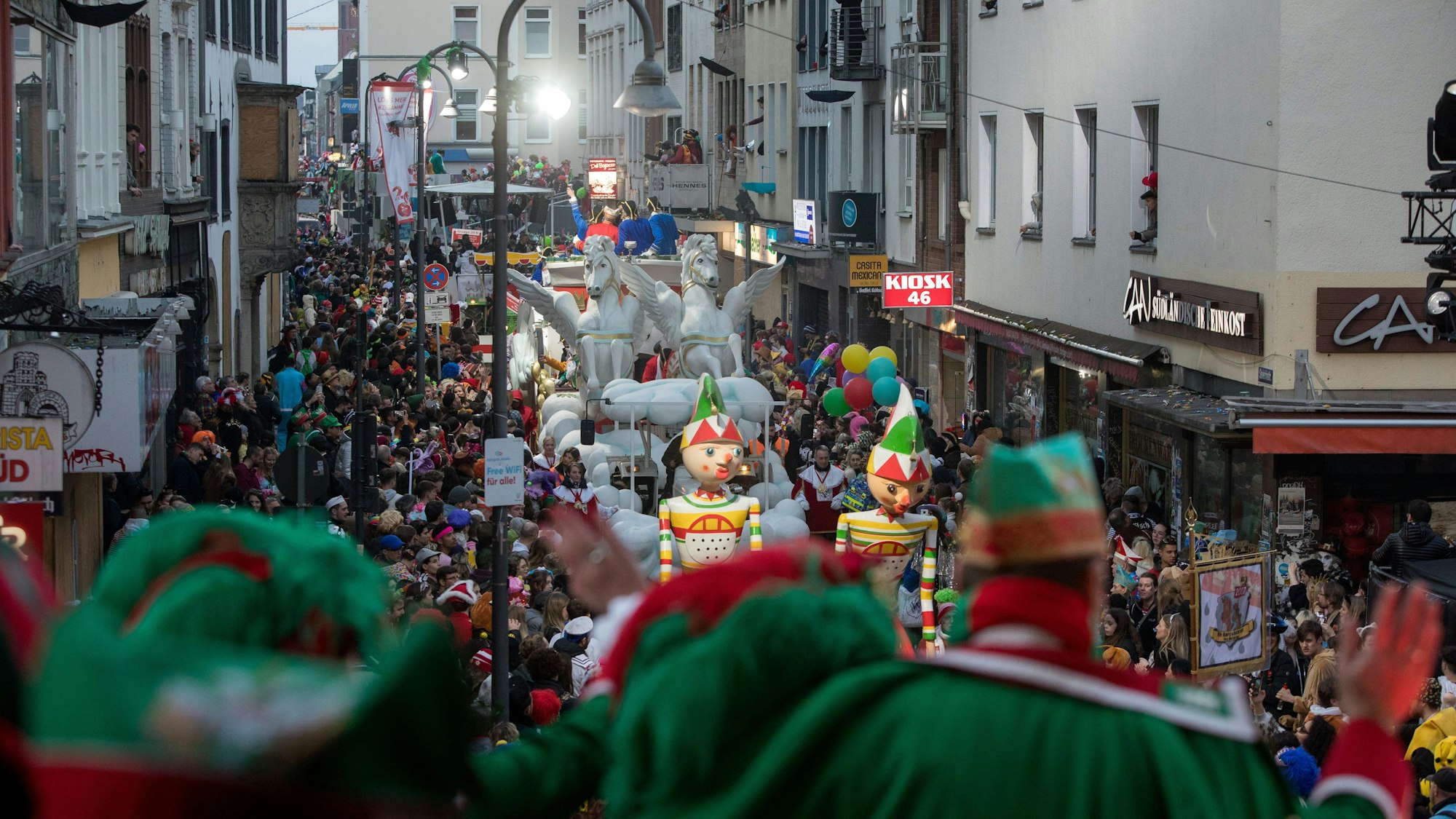 Blick von einer Tribüne auf den Rosenmontagszug, der auf der Kölner Severinstraße entlangläuft.