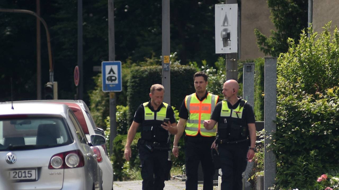 Drei männliche Mitarbeiter des Ordnungsdienst gehen an einer Straße entlang und informieren die Anwohner über eine Evakuierung.