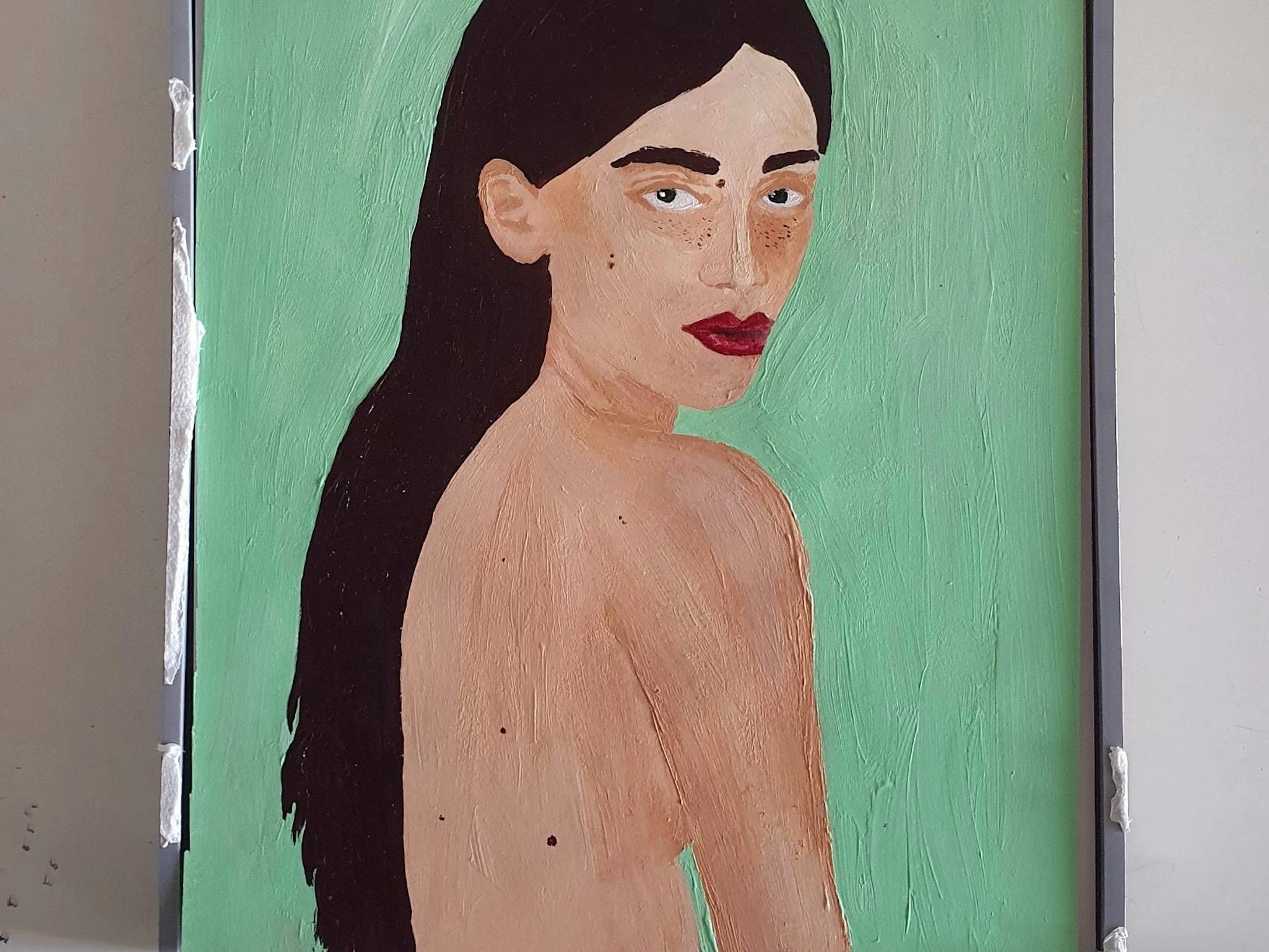 Eine Frau mit nacktem Oberkörper und langen dunklen Haaren guckt über ihre Schulter.