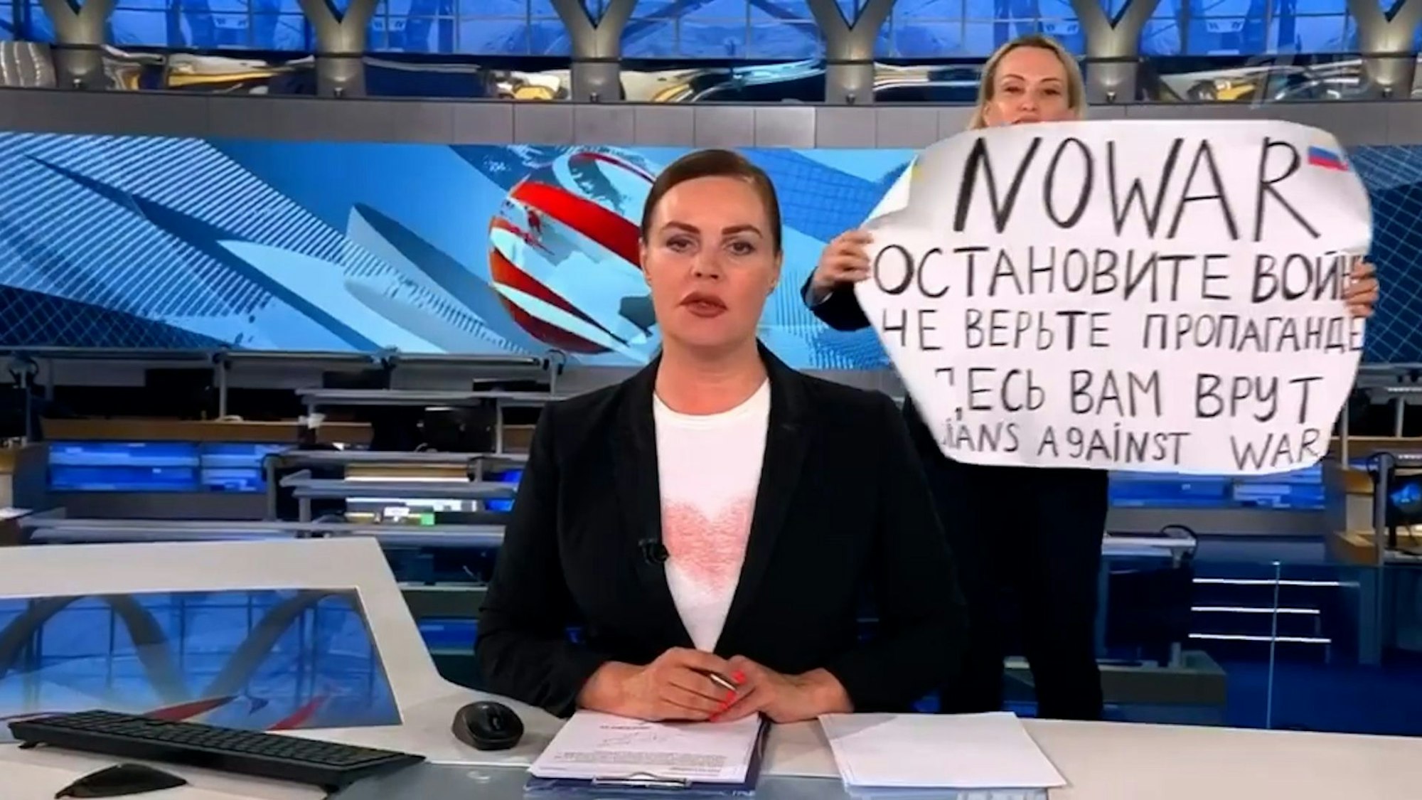 Der Screenshot aus der abendlichen Hauptnachrichtensendung des russischen Staatsfernsehen zeigt Redakteurin Marina Owsjannikowa (r) mit einem Protestplakat mit der Aufschrift „Stoppt den Krieg. Glaubt der Propaganda nicht. Hier werdet ihr belogen“ hinter der Nachrichtensprecherin Jekaterina Andrejewa.