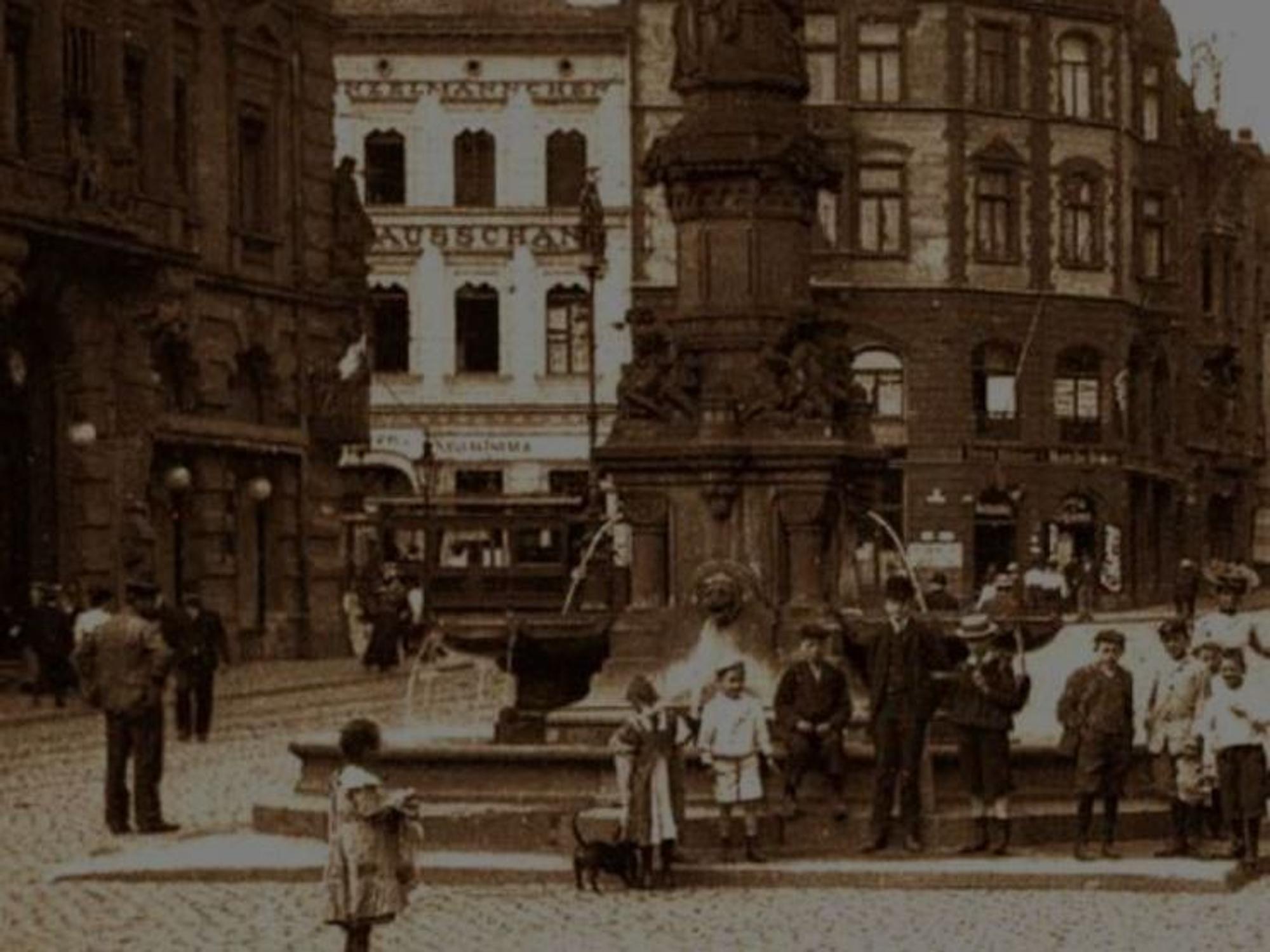 Historisches Foto mit Kölnerinnen und Kölnern vor einem Brunnen.