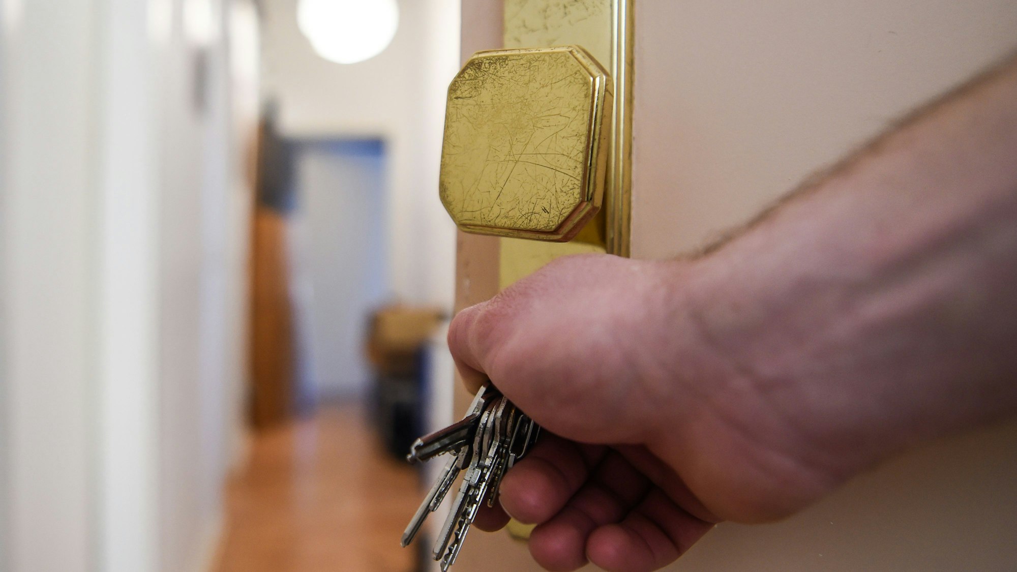 Ein Mann schließt eine Wohnungstür auf und öffnet sie.