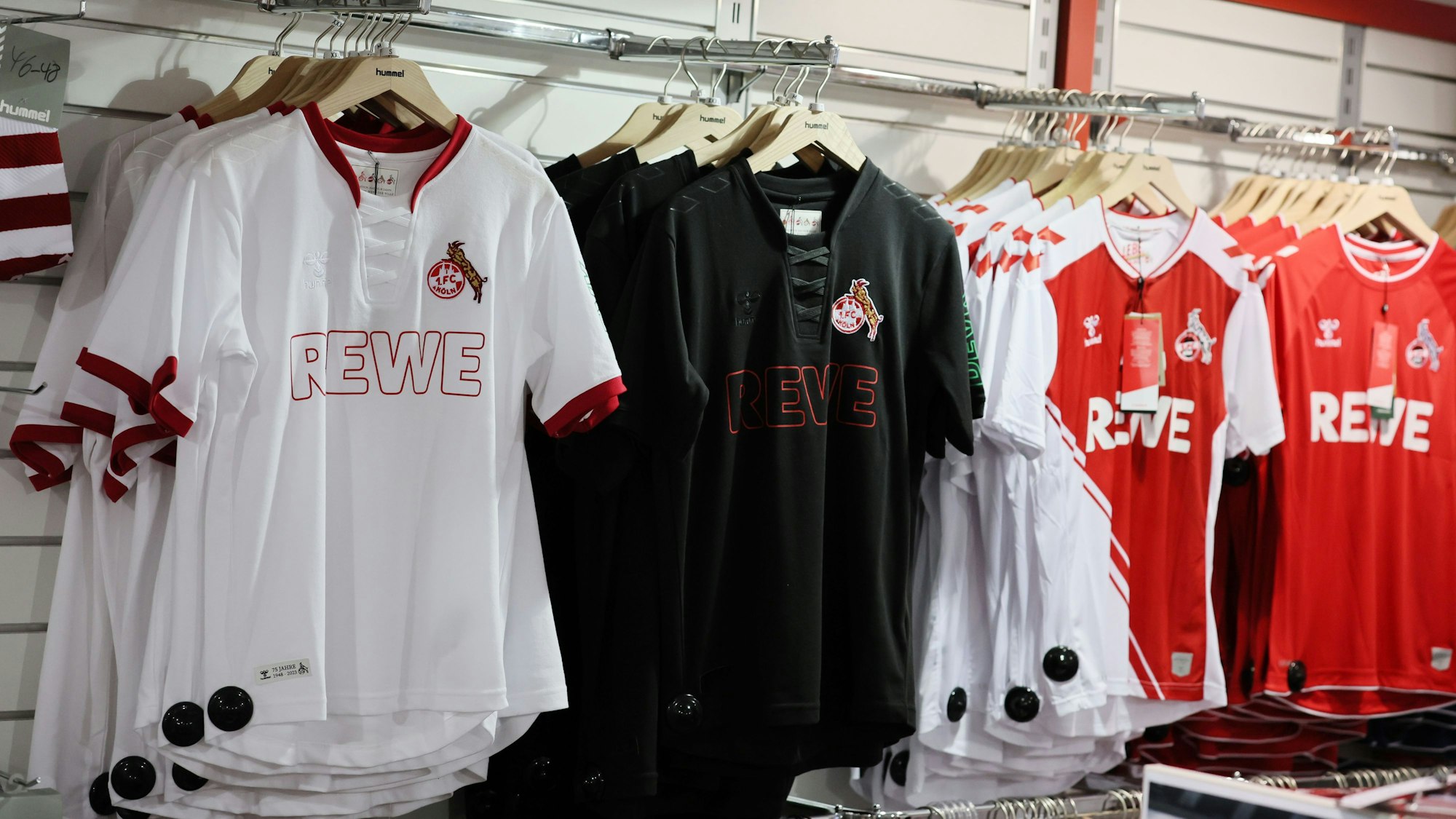 Verschiedene Trikots des 1. FC Köln hängen im Fanshop an der Wand.
