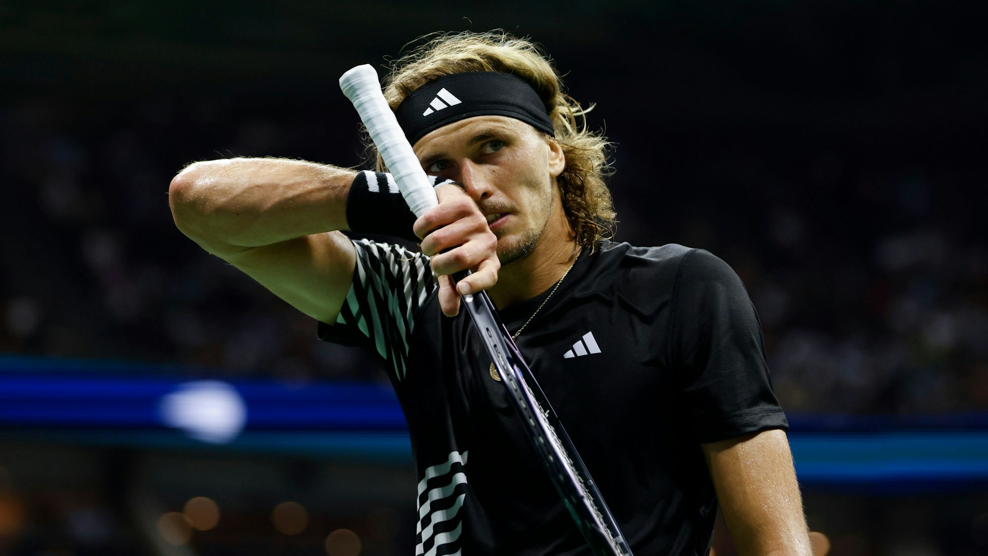 Alexander Zverev wischt sich das Gesicht ab.