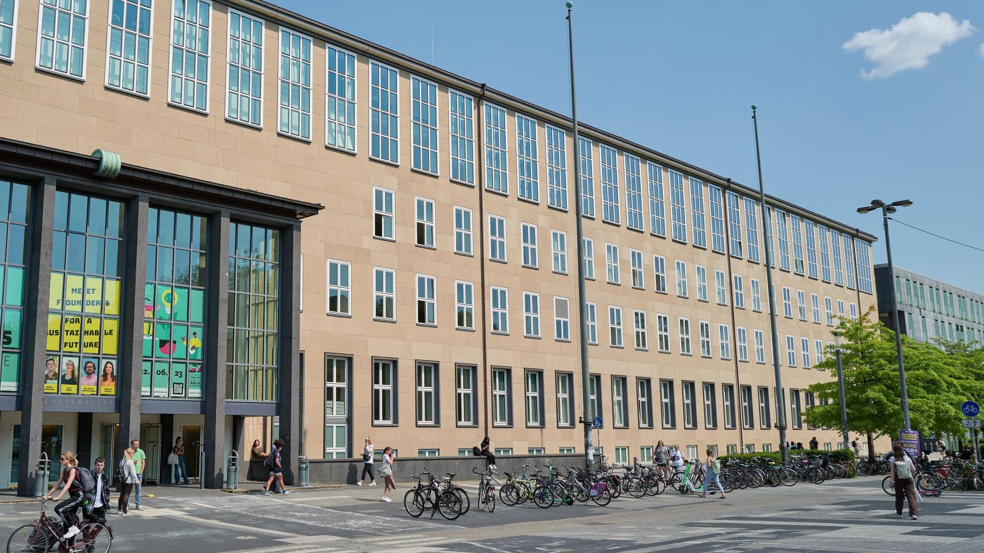 Der Haupteingang der Universtät zu Köln, einige Menschen sind davor unterwegs.