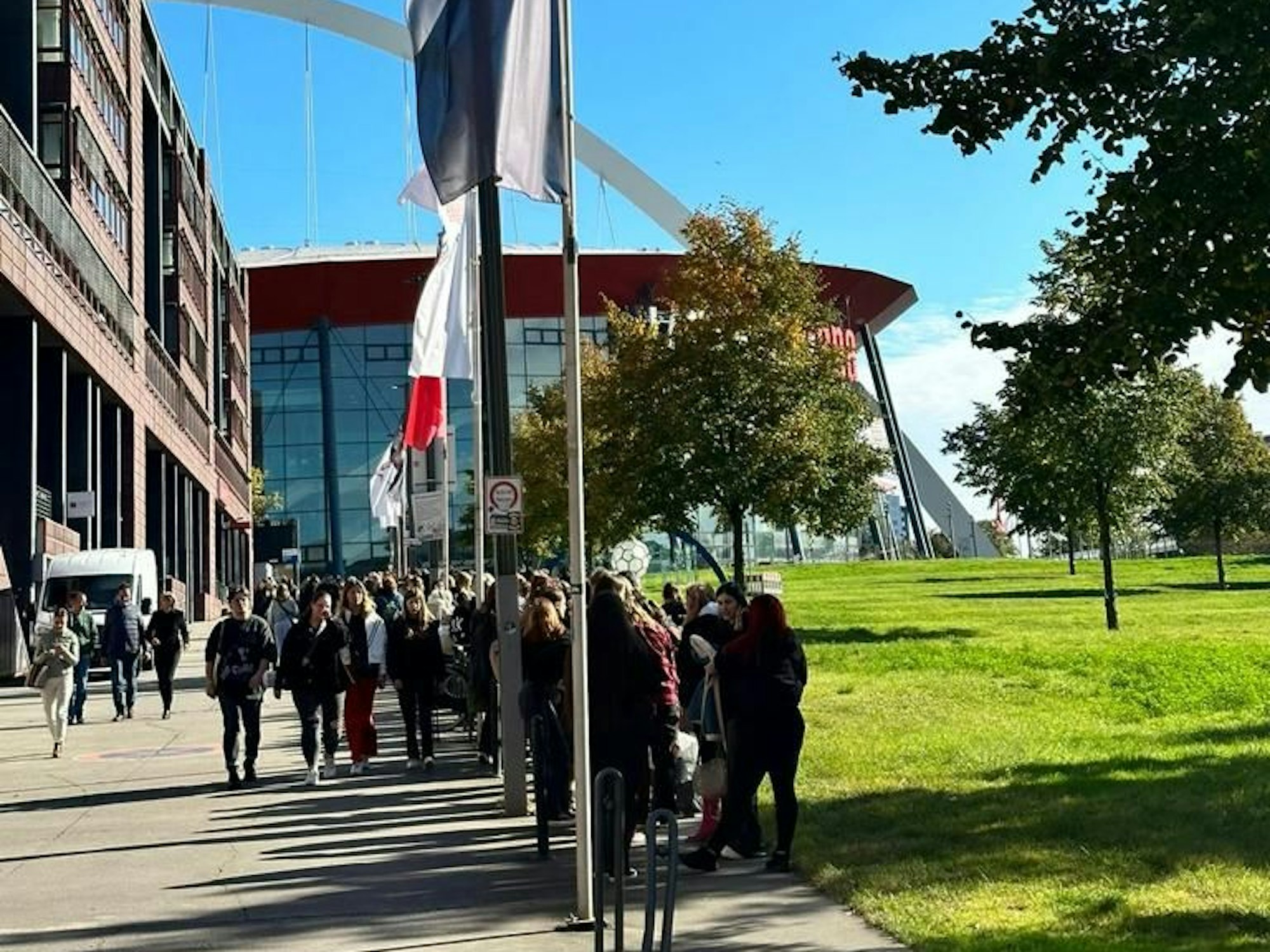 Menschen stehen vor der Lanxess-Arena in einer Schlange.