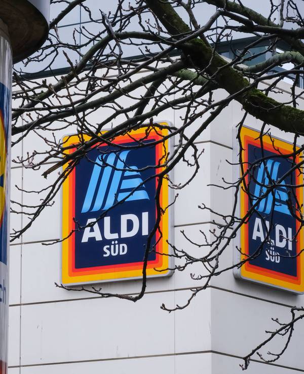 Eine mit einem Lidl-Logo beklebte Säule steht in Düsseldorf vor einer Aldi-Süd-Filiale.
