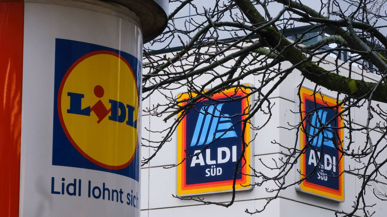 Eine mit einem Lidl-Logo beklebte Säule steht in Düsseldorf vor einer Aldi-Süd-Filiale.