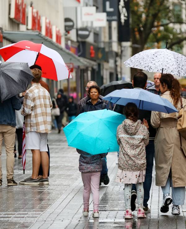 Menschen mit Regenschirmen laufen über die Fußgängerzone der Hohe Straße.