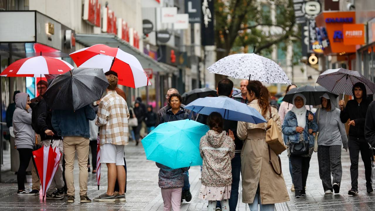 Menschen mit Regenschirmen laufen über die Fußgängerzone der Hohe Straße.