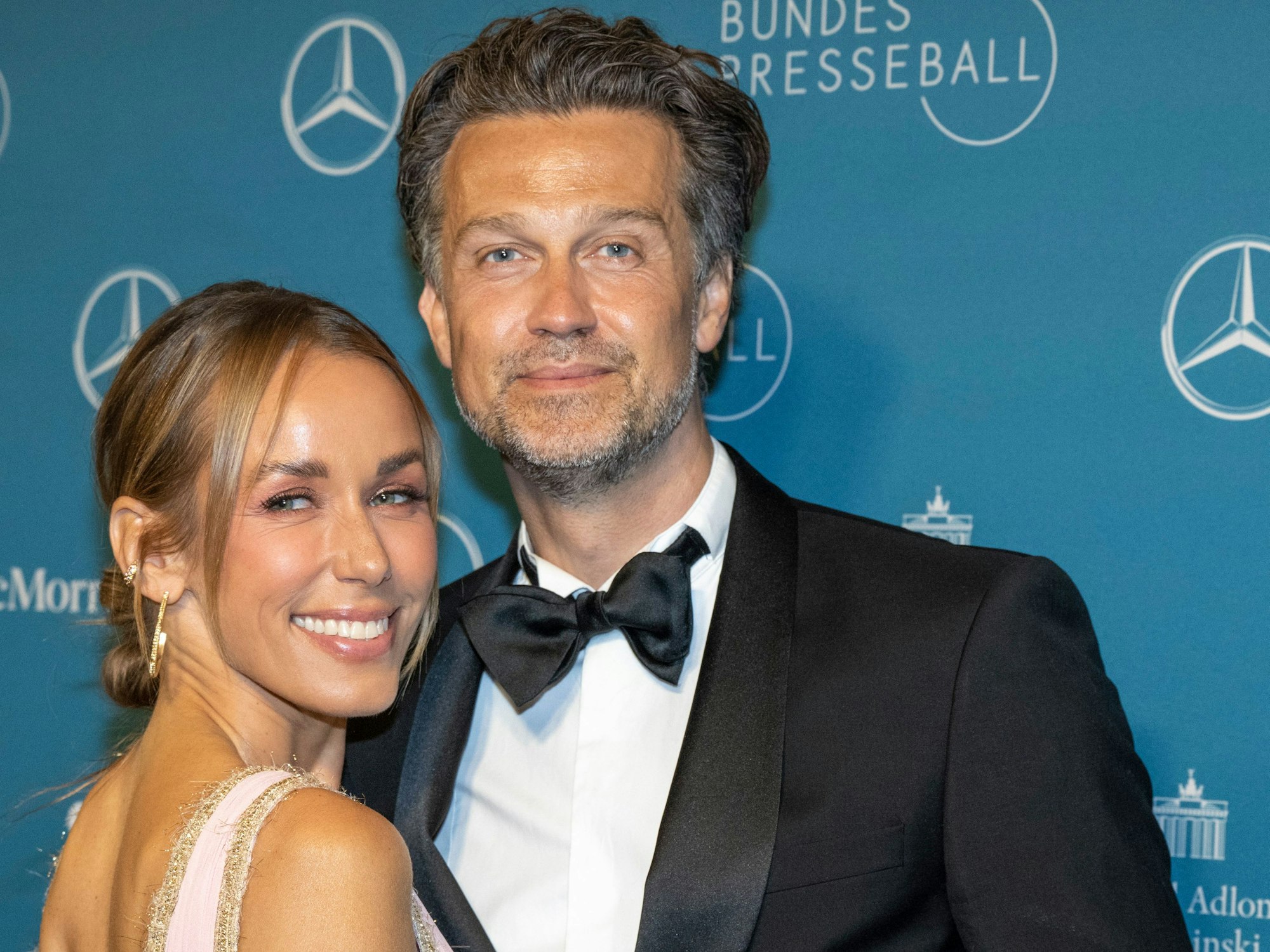 Moderatorin Annemarie Carpendale und ihr Ehemann Wayne Carpendale kommen am 29. April 2022 zum 69. Bundespresseball ins Hotel Adlon. Beide lächeln in die Kamera, Wayne Carpendale, der Black Tie trägt, hat einen Arm um Gattin Annemarie im zartrosa Kleid gelegt.