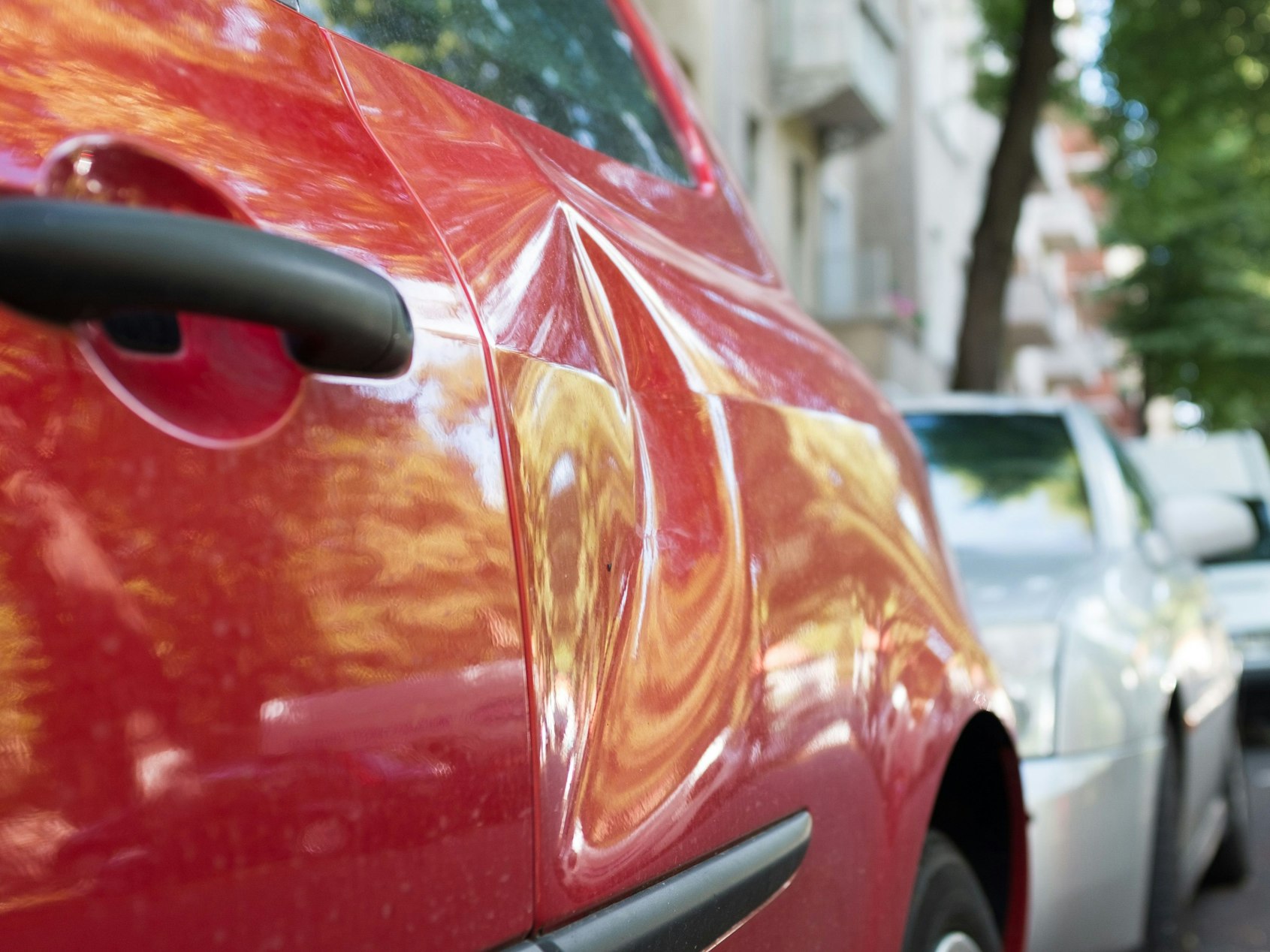 Ein Auto mit einer Delle parkt am Straßenrand.