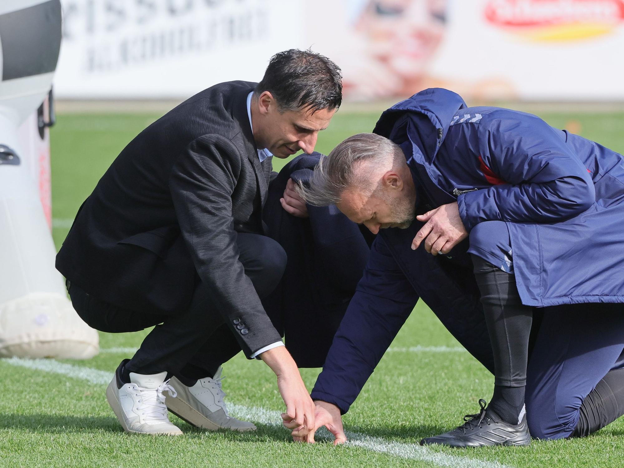 Christian Keller und Uwe Gospodarek untersuchen die Stelle im Rasen, an der sich Philipp Pentke verletzt hat.