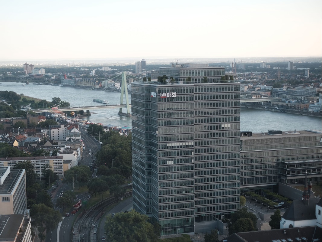 Luftaufnahme, die den Verwaltungssitz von Lanxess in Köln-Deutz zeigt. Im Hintergrund sind der Rhein und mehrere Kölner Brücken zu sehen.